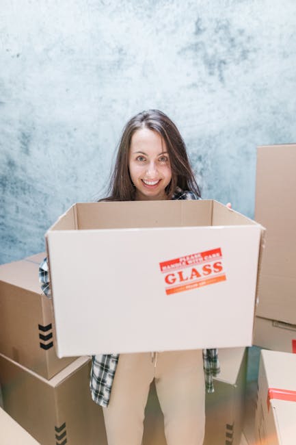 A man with dark hair and a beard, dressed in a grey t-shirt, and a woman with curly blonde hair, wearing a grey top, are inside a room during a home relocation process. They are examining a document o